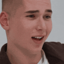 a close up of a young man 's face with a chain around his neck
