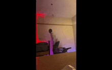 a man is standing on a chair in a room with a bed and a chair .