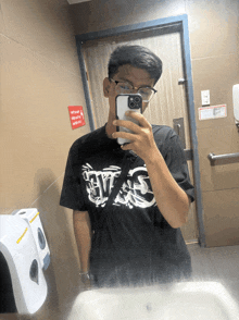 a man taking a selfie in a bathroom with a sign that says no smoking