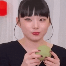 a woman is holding a green object in her hands and looking at the camera .