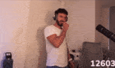 a man wearing headphones is singing into a microphone with the number 12603 on the bottom right