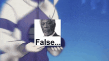 a person holding a picture of a man and the word false