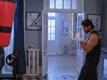 a man wearing boxing gloves is standing in front of a punching bag in a room .