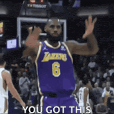 lebron james is wearing a purple lakers jersey and waving his hand .