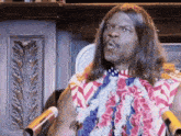 a man with long hair is standing in front of a microphone wearing an american flag shirt