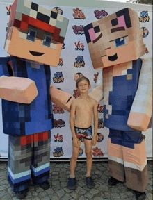 a boy stands between two minecraft mascots in front of a backdrop that says vito shop