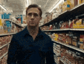 a man in a black shirt is standing in a grocery store aisle .