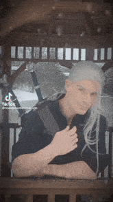 a man with long white hair is holding a sword in his right hand and a tiktok of him