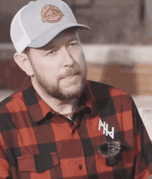 a man wearing a plaid shirt and a hat has the letter a on his shirt