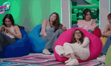 a group of women are sitting on bean bag chairs in front of a sign that says ' ninja versus '