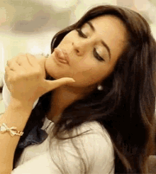 a woman with long hair is making a funny face and giving a thumbs up sign .