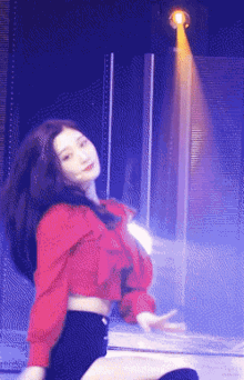 a woman in a red shirt and black shorts is dancing