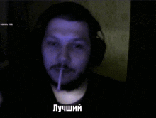 a man wearing headphones lighting a cigarette with the word " лучший " in the lower right corner