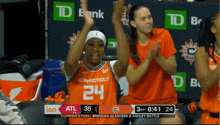 a woman wearing a connecticut jersey is clapping