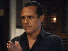a man wearing a black shirt is clapping his hands together