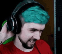 a man with green hair wearing headphones and a red shirt .