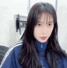 a young woman with long hair is wearing a blue jacket with white stripes on the sleeves .