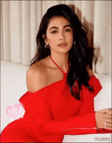 a woman in a red dress is sitting on a white couch .