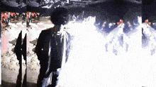 a man in a black jacket is standing in front of a crowd of people in a dark room .