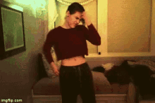 a man in a crop top is standing in front of a window .