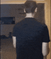 a man in a black shirt is standing in front of a door in a living room .