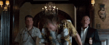 a man with a crown on his head is standing in a room with other men .
