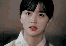 a close up of a woman 's face with a white shirt and red lipstick .