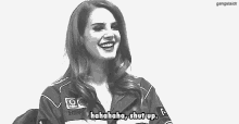 a black and white photo of a woman wearing a racing jacket laughing .