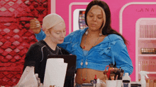 a woman in a blue crop top stands next to another woman in a black shirt