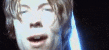 a close up of a man 's face with his eyes closed and a light behind him .