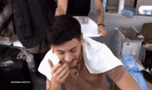 a man with a towel around his neck is smiling and eating something