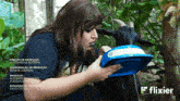 a woman is feeding a goat from a blue container that says bappro