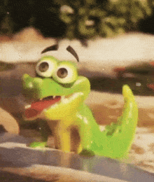 a green and yellow toy crocodile is sitting on a rock in a pool .