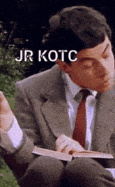 a man in a suit and tie is reading a book with the words jr kotc written above him