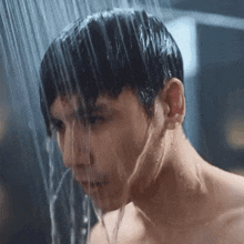 a shirtless man taking a shower with water coming out of his mouth