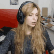 a woman with long blonde hair wearing headphones and a gray shirt