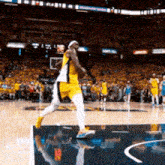 a basketball player in a yellow and white uniform is dribbling a ball