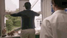 a man in a blue shirt is looking out a window