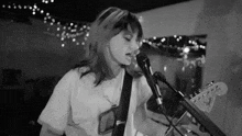 a woman is playing a guitar and singing into a microphone .