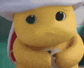 a yellow cartoon character with green eyes and a white hat