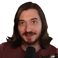 a man with long hair and a beard is speaking into a microphone