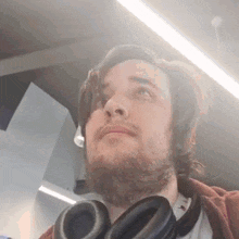 a man with a beard is wearing headphones and looking up at the ceiling .