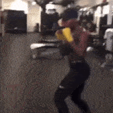 a man is boxing in a gym without a shirt on and wearing yellow gloves .