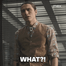 a man wearing a vest and a floral shirt says " what "
