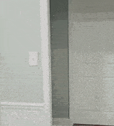a man in a white shirt is peeking out of a doorway
