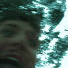 a blurry picture of a person 's face with a tree in the background