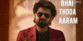 a man wearing sunglasses and a red jacket says " bhai thoda aaram " on the bottom