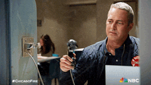 a man is holding a phone in front of a laptop with the hashtag #chicagofire