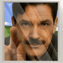 a man with a mustache is pointing his finger at the camera