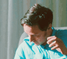 a man in a blue shirt is sitting on a couch and smoking a cigarette